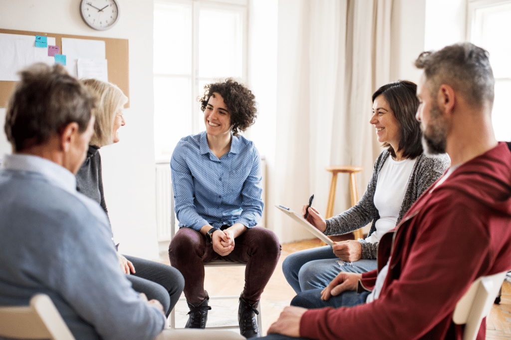 A group counseling session with five participants seated in a circle, engaging in a supportive and open discussion.