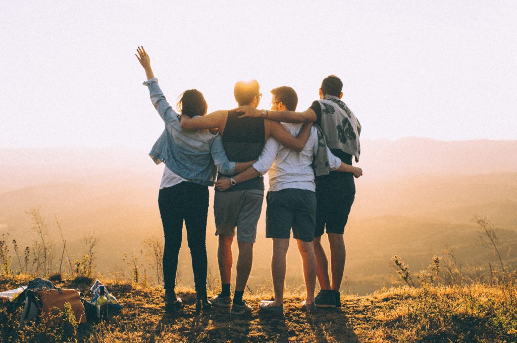 A group of friends standing together with arms around each other, embodying support and community that are important in the addiction recovery and treatment.